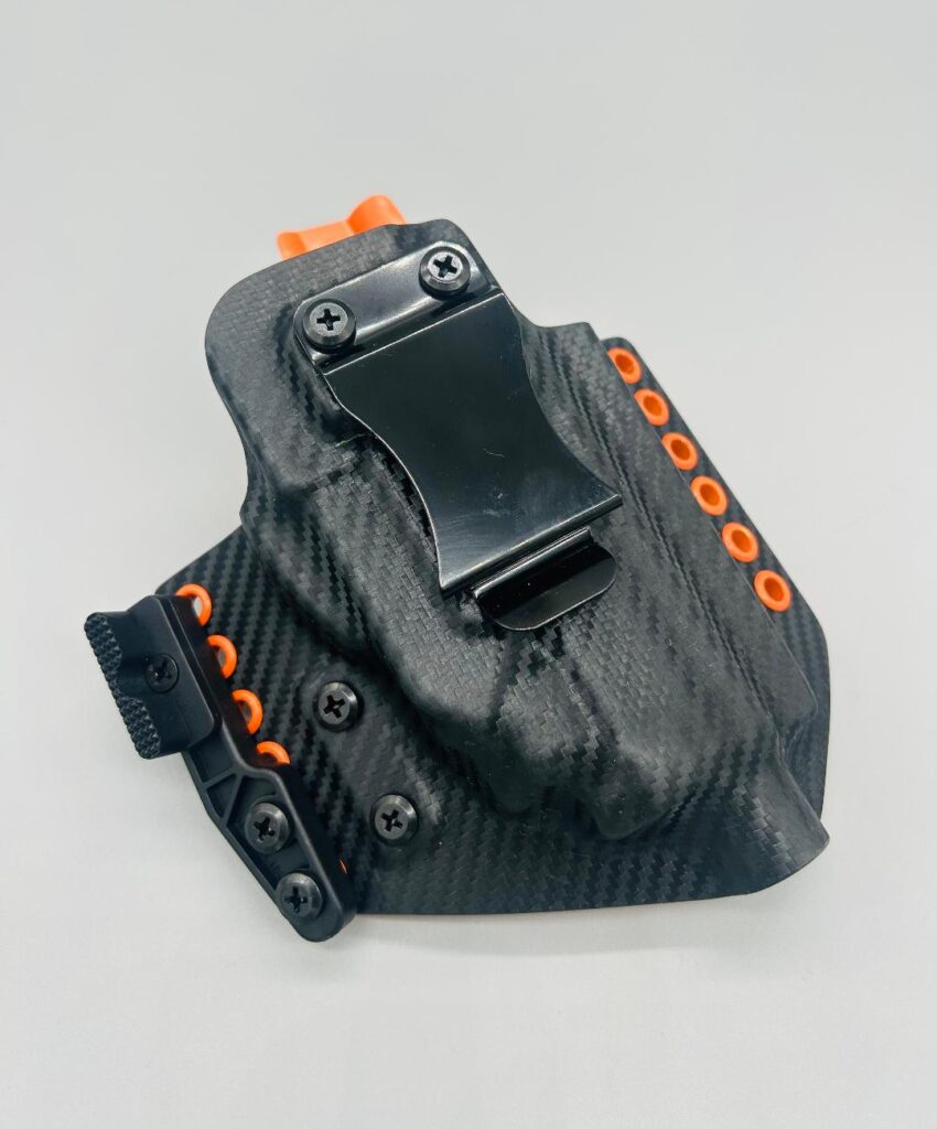Black carbon fiber Theseus 2.0 Kydex IWB holster with orange hardware and a claw